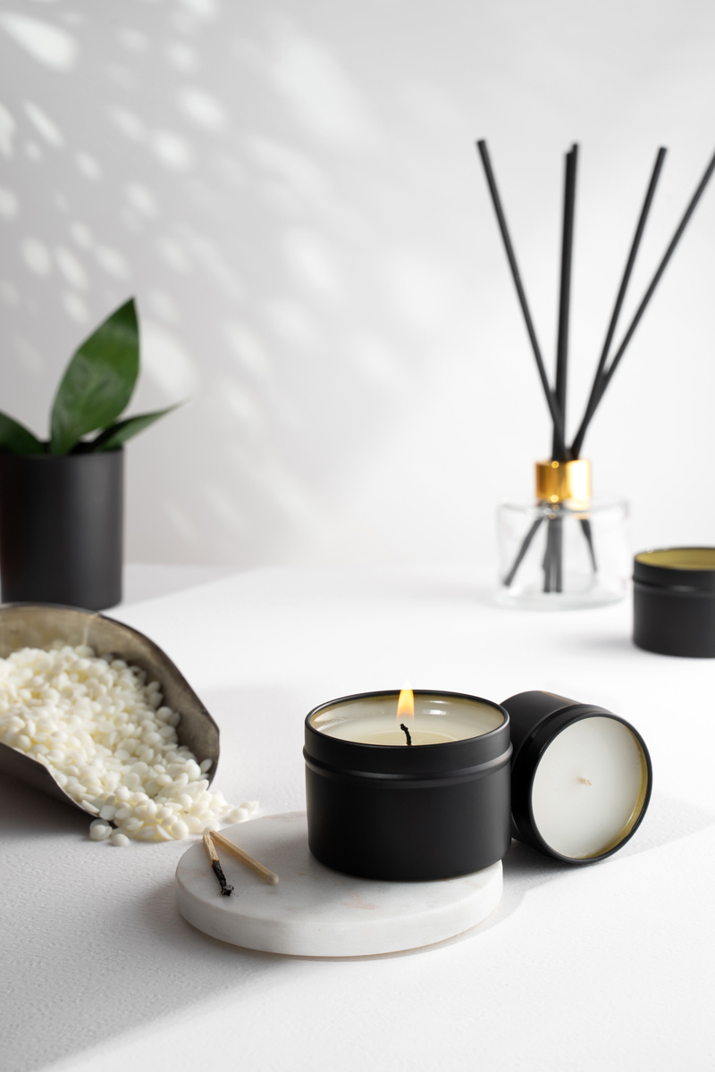 Soy Wax Candle in a Black Jar, and Green Leaf, Plant on a White Background. Natural Eco Friendly Organic Wax Candles. Trendy Concept. Minimalist. Isometric Projection. Copy Space.